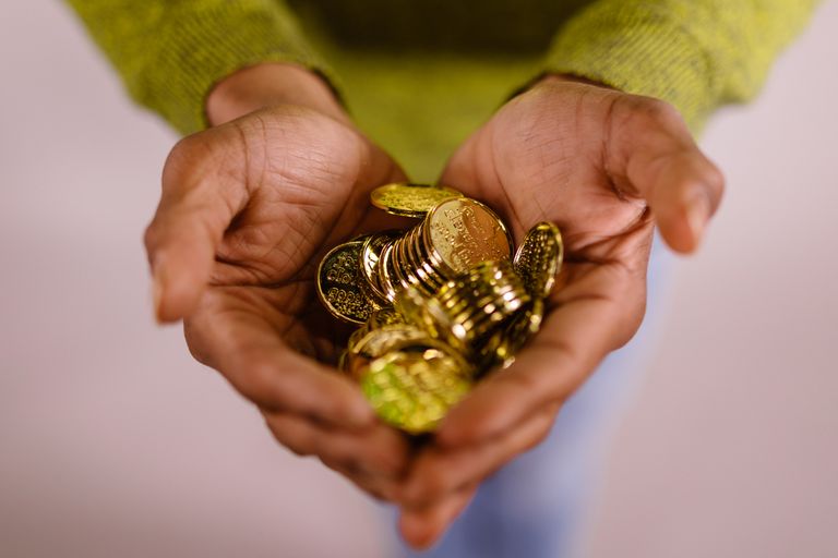 Close-up of hands cupping shiny gold coins, symbolizing wealth and prosperity.